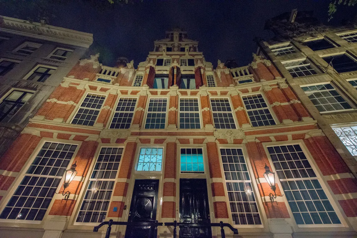 Lit historic gabled facade in Amsterdam after dark