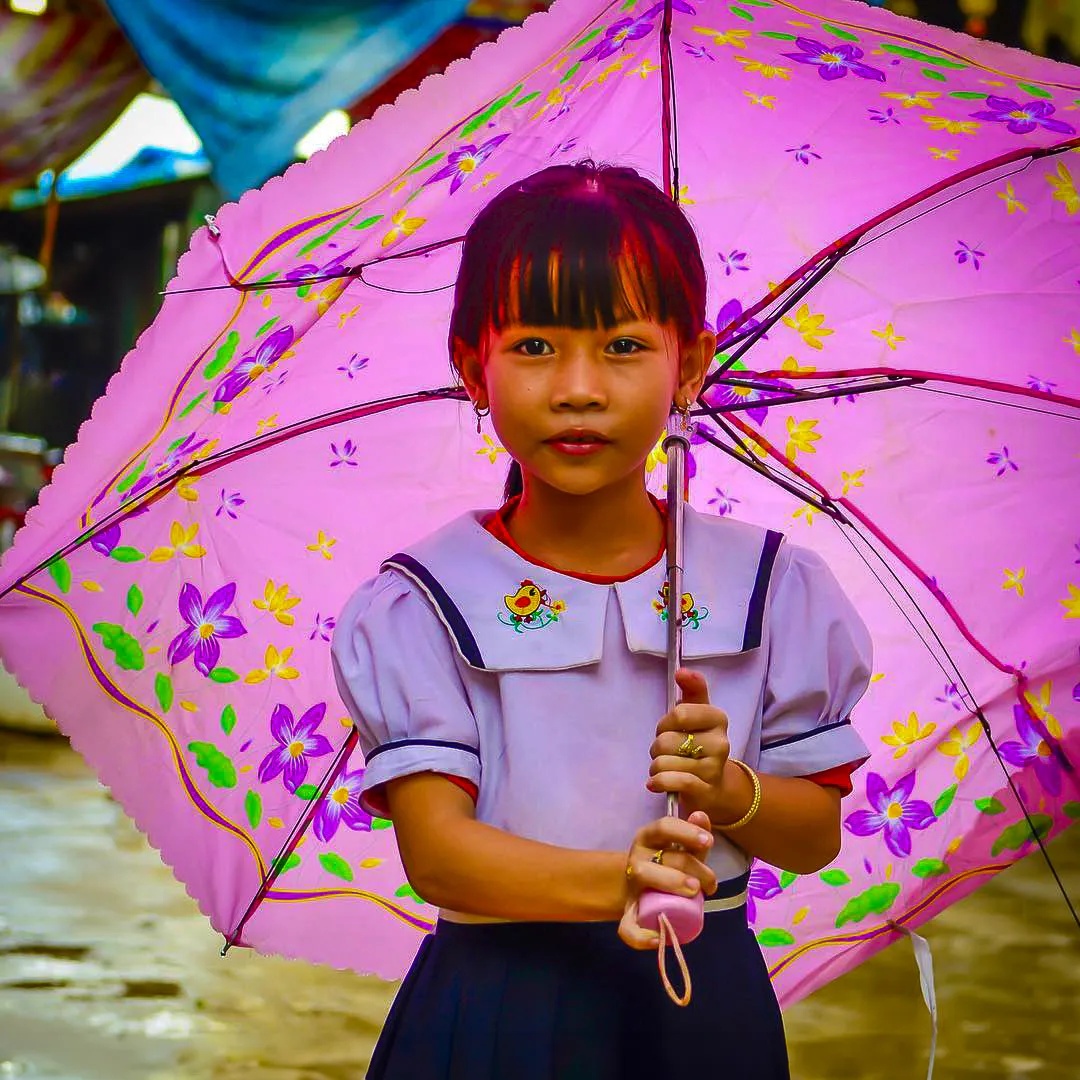 Cambodian schoolgirl under a pink flowered umbrella