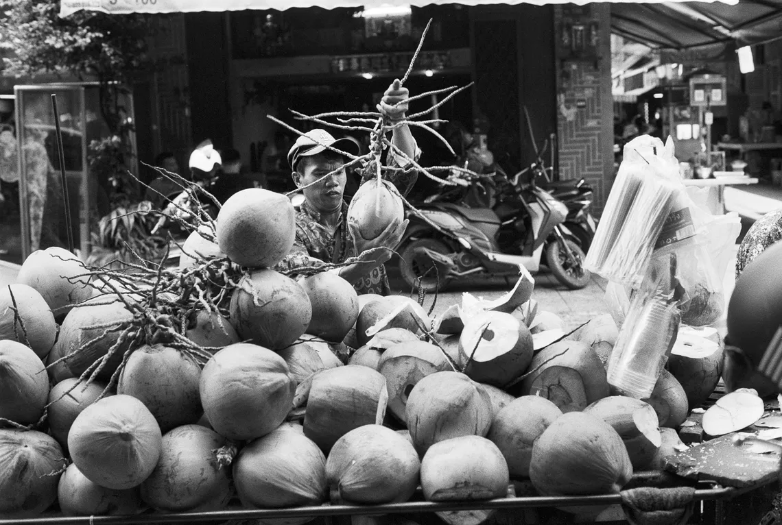 A heavily loaded coconut cart in a Phnom Penh street, black and white