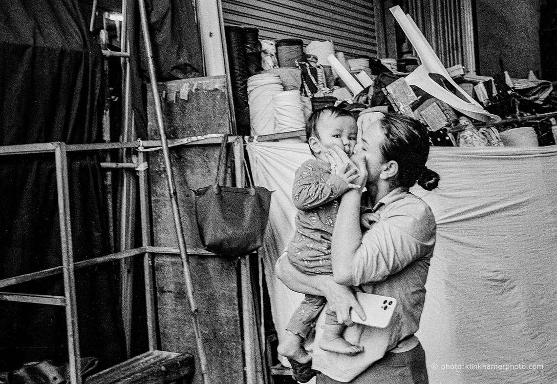 A mother holding her small child in a Phnom Penh side street, black and white