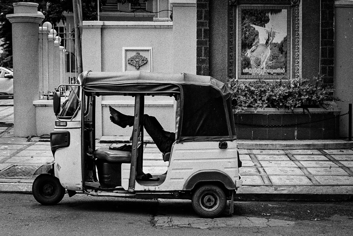 A tuk tuk parked on a colonial street in Phnom Penh, black and white