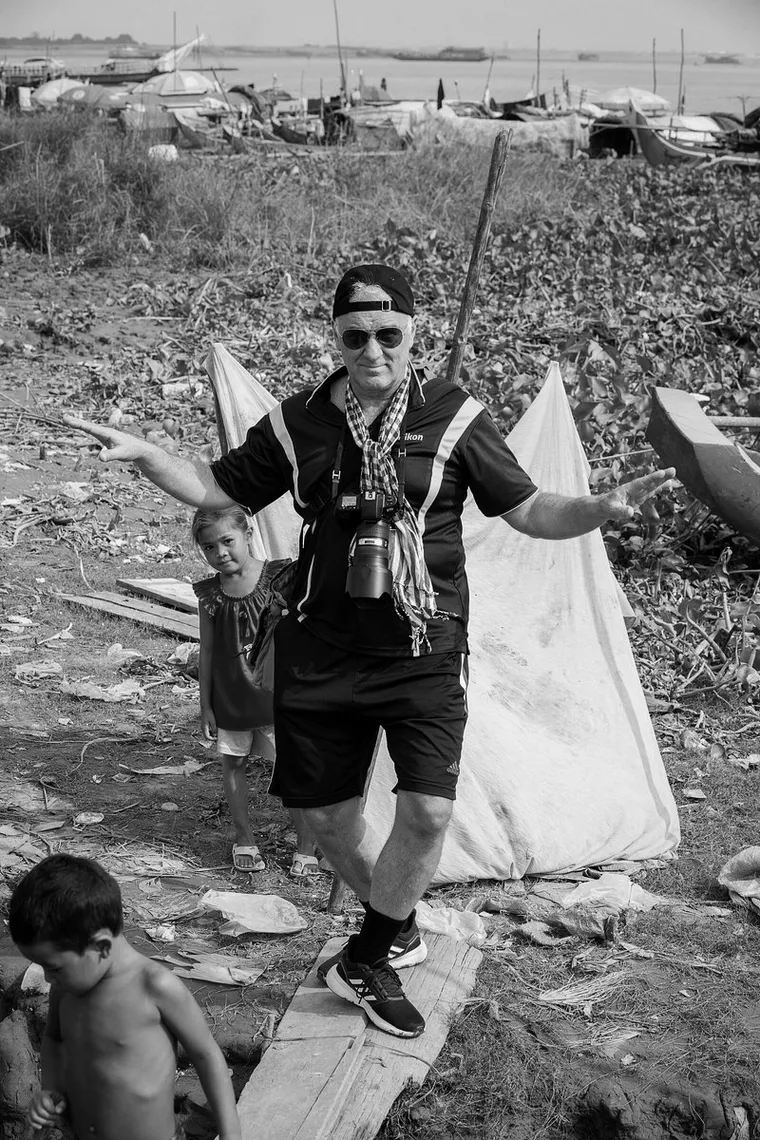 Michael Klinkhamer standing with his arms spread on a plank bridge in Cambodia, black and white