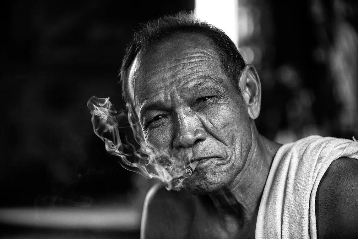 Elderly Cambodian man smoking, black and white portrait