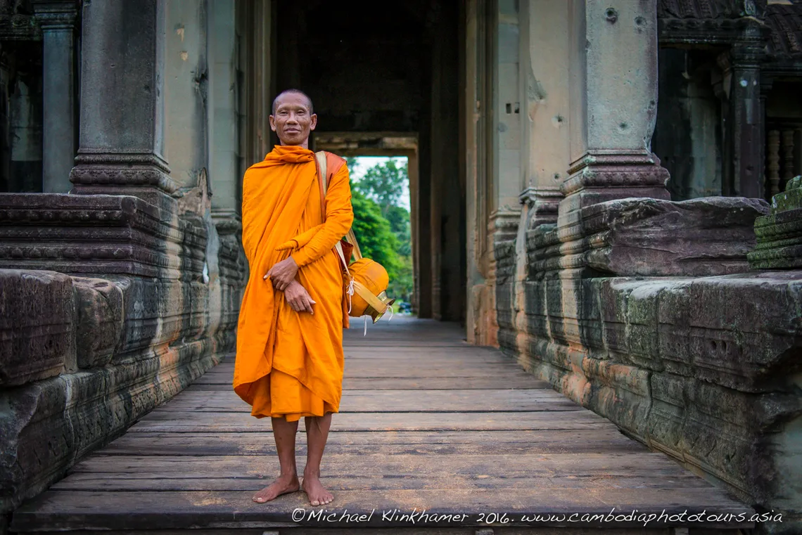Monk in an orange robe in a temple doorway at Angkor