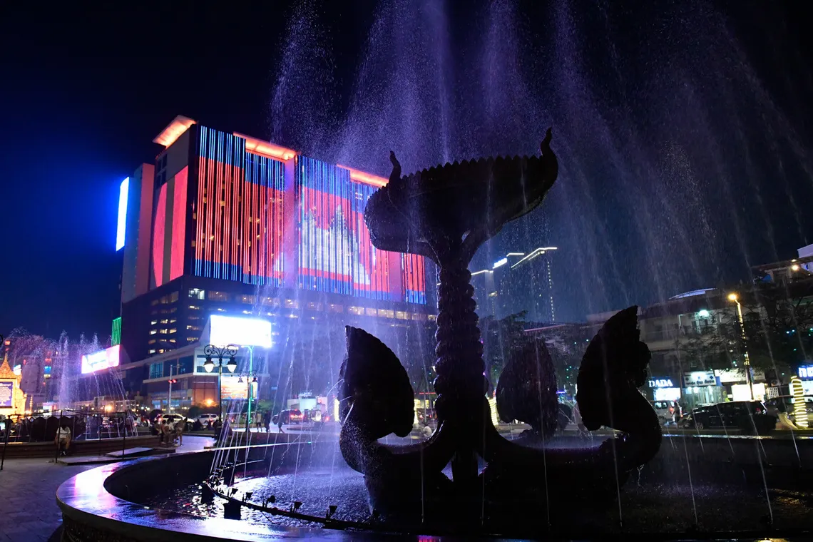 Neon lit fountain and night traffic in Phnom Penh