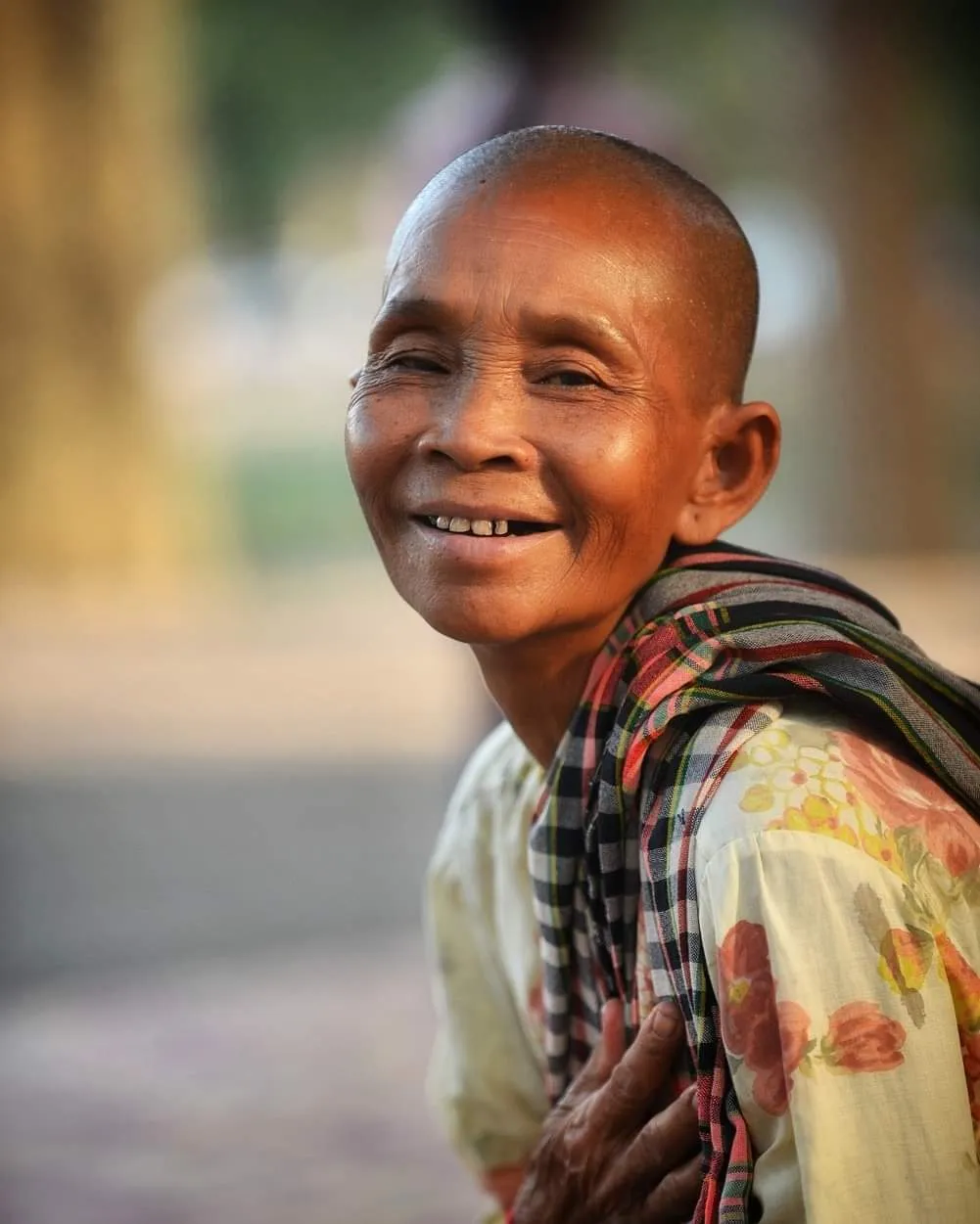 Smiling elderly Khmer woman in a temple courtyard